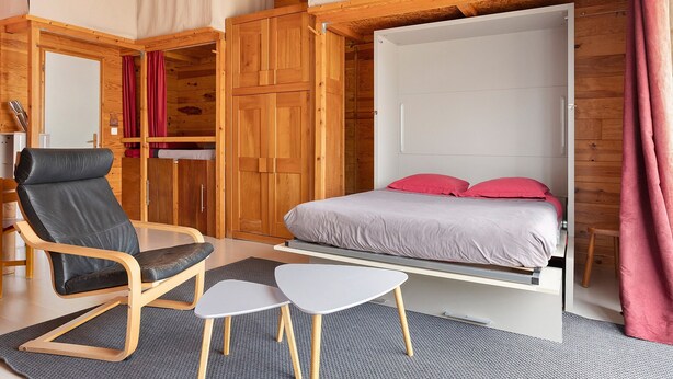 Ein gemütliches Schlafzimmer mit einem Bett, einem Sessel und einem kleinen Tisch.