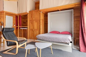 A compact bedroom with a bed, a chair, and a small table.