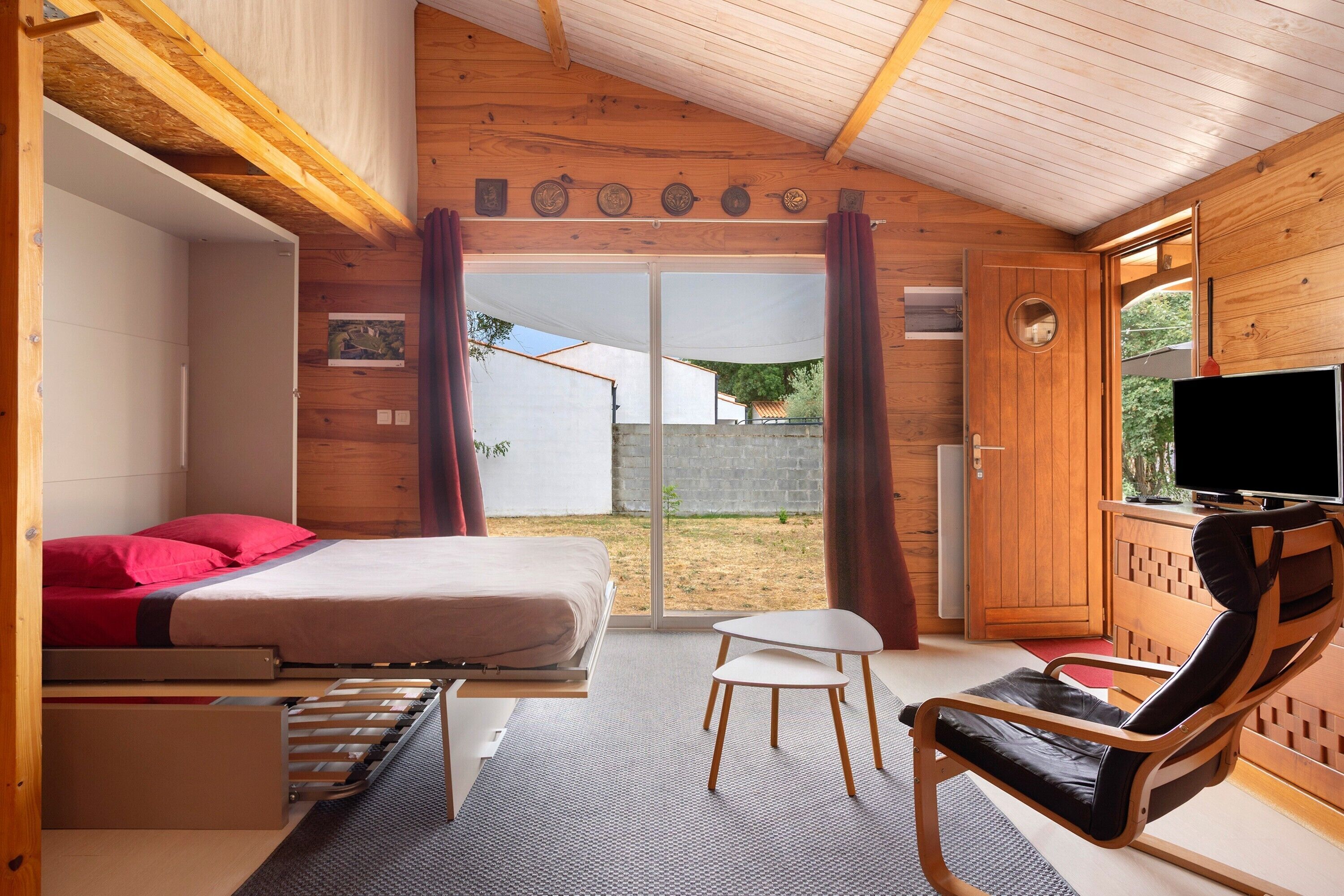 Una habitación con cama, televisión, sillón y una mesita.