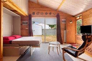 A room with a bed, a TV, a chair, and a small table.