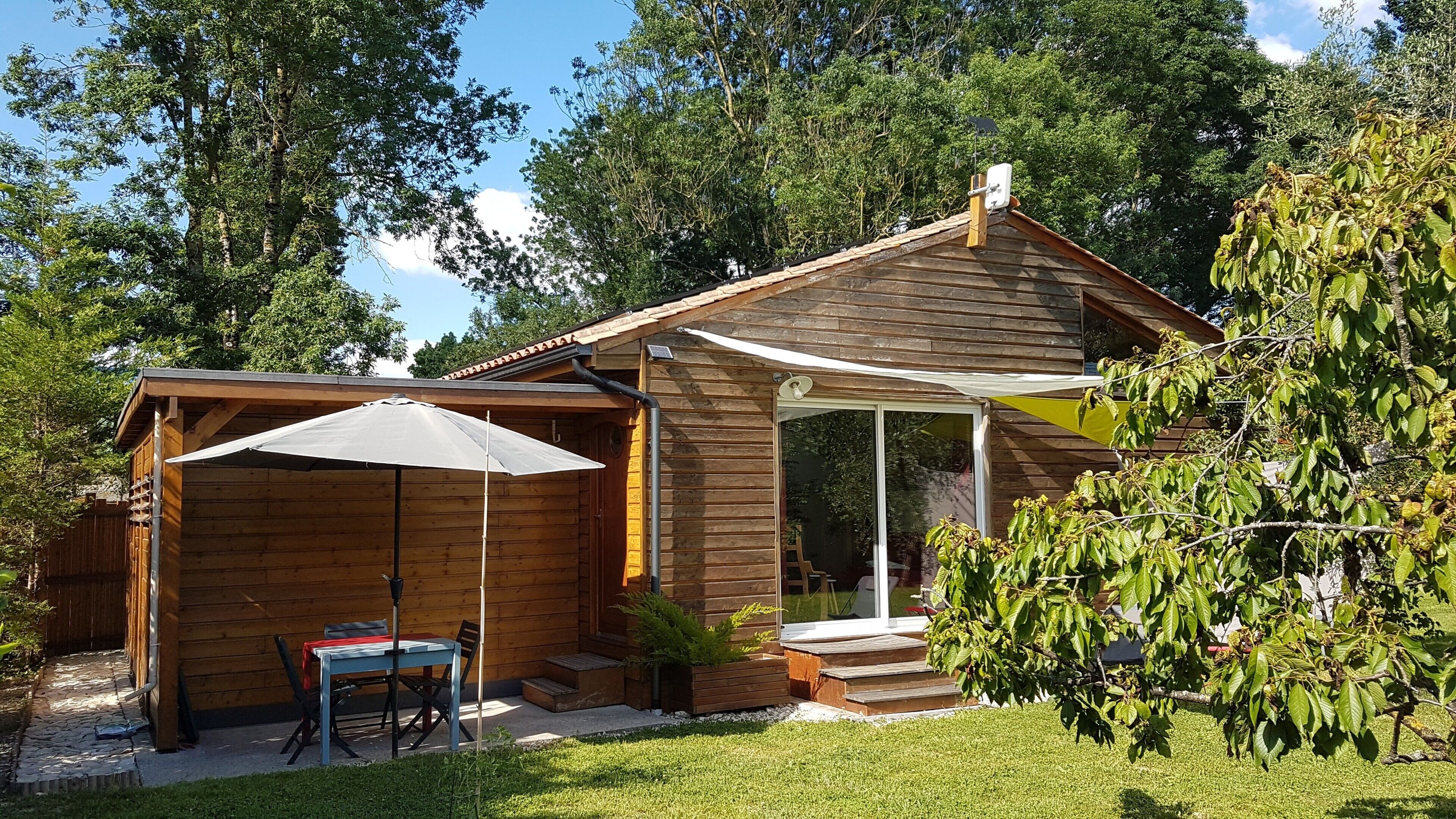 A wooden cabin with a covered patio, a table, and chairs.