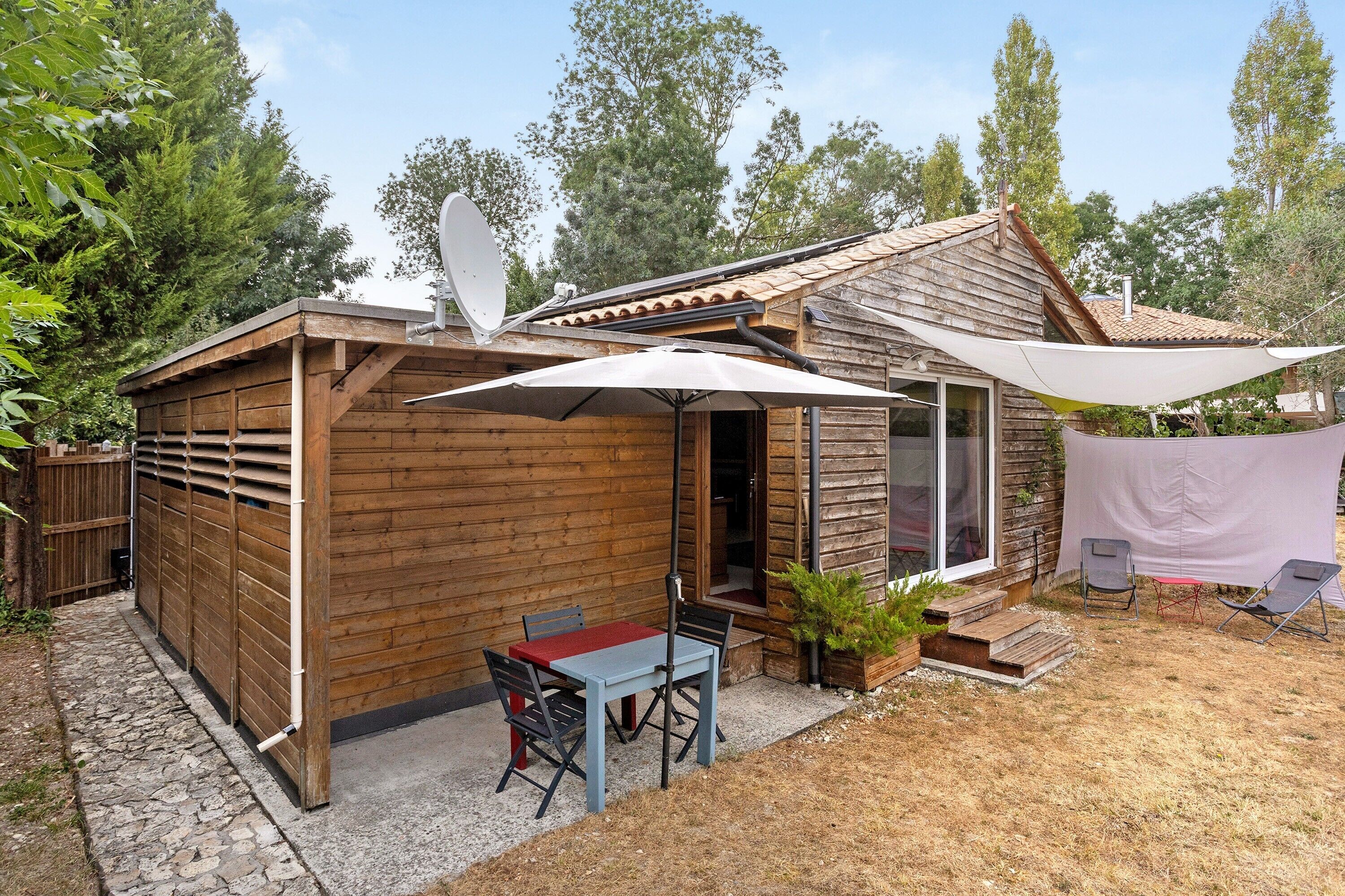 A wooden cabin with a patio area, a table, and two chairs.