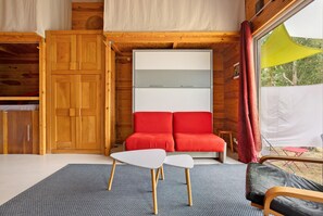 Et værelse med træpaneler, en rød sofa, et hvidt bord og et vindue med et gult gardin.
