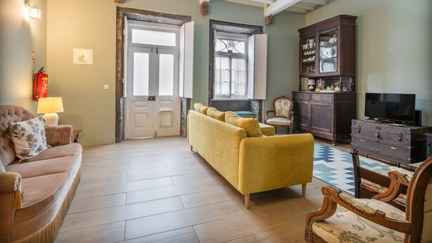 Una sala de estar con sofá, sillón, aparador y televisión.