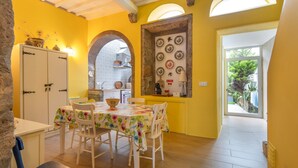 Un comedor con una mesa lista para cuatro personas, un armario blanco y vistas a una cocina a través de un arco.