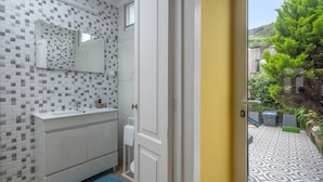 Un baño con pared de azulejos, un lavamanos blanco y una alfombra azul.