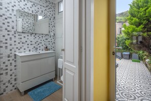 A bathroom with a tiled wall, a white sink, and a blue rug. - Holiday Home 'Casa Império - Azorean House' with Mountain View, Private Terrace and Wi-Fi (Povoação)