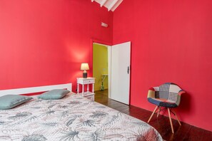 Ein Schlafzimmer mit einem Bett, einem Sessel, einem Nachttisch und einer Tür zu einem anderen Raum.