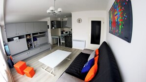 Ett modernt vardagsrum med en soffa, en pall och ett matbord.