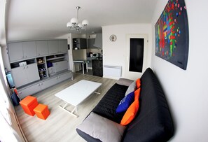 A modern living room with a sofa, ottoman, and a dining table. - Charming family studio by the white sea at Le Letty in Bénodet (Bénodet)