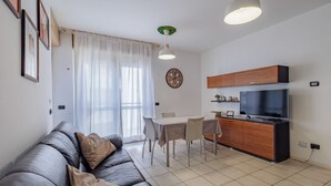 Een moderne woonkamer met een bank, eettafel en keukenhoek.