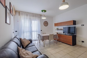 A modern living room with a sofa, dining table, and kitchen area. - Comfortable 50m2 apartment, ideal for 2 people, located on the third floor of a building with a lift.The accommodation is located in a strategic position less than 1.5 km from the center of Bergamo and the train station, easily reachable both on foot and (Bergamo)