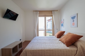 A bedroom with a bed, a TV mounted on the wall, and a window with curtains. - Comfortable 50m2 apartment, ideal for 2 people, located on the third floor of a building with a lift.The accommodation is located in a strategic position less than 1.5 km from the center of Bergamo and the train station, easily reachable both on foot and (Bergamo)