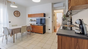 Een moderne keuken met een eethoek, houten kastjes, een inbouwoven en een koffieapparaat.