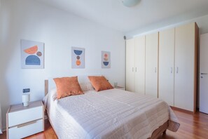 A bedroom with a bed, nightstand, wardrobe, and abstract wall art. - Comfortable 50m2 apartment, ideal for 2 people, located on the third floor of a building with a lift.The accommodation is located in a strategic position less than 1.5 km from the center of Bergamo and the train station, easily reachable both on foot and (Bergamo)
