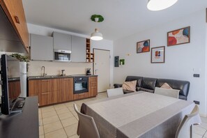 A modern kitchen with wooden cabinets, a built-in oven, and a dining area with a table and chairs. - Comfortable 50m2 apartment, ideal for 2 people, located on the third floor of a building with a lift.The accommodation is located in a strategic position less than 1.5 km from the center of Bergamo and the train station, easily reachable both on foot and (Bergamo)