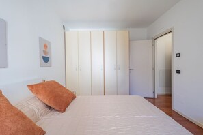 A bedroom with a bed, two pillows, a wardrobe, and a door leading to another room. - Comfortable 50m2 apartment, ideal for 2 people, located on the third floor of a building with a lift.The accommodation is located in a strategic position less than 1.5 km from the center of Bergamo and the train station, easily reachable both on foot and (Bergamo)