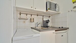 Una cocina compacta equipada con lavadora integrada, microondas y lavaplatos.