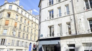 Un immeuble à plusieurs étages, avec une entrée au rez-de-chaussée, de grandes fenêtres et des balcons.