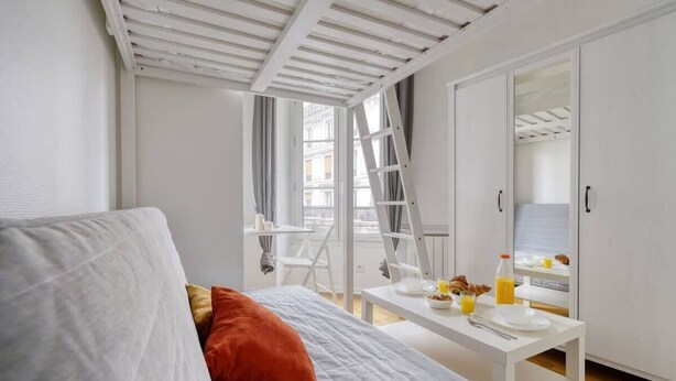 Une chambre avec un lit, une table où le petit-déjeuner est servi, une échelle et une armoire.