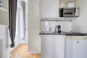 A compact kitchen with a microwave, sink, and dishwasher. - Homey Studio - Coeur du 17em-Bail moyenne durée 2D (Paris)