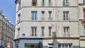 Un edificio de varios pisos con balcones, un escaparate visible y un cielo despejado.