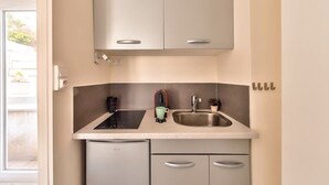 Una cocina compacta con lavavajillas integrado, un lavamanos y una pequeña encimera.