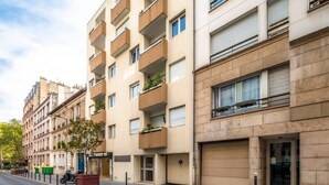 Un edificio residencial de varios pisos con balcones, una tienda a la vista y una moto estacionada.