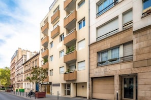 A multi-story residential building with balconies, a visible storefront, and a parked scooter. - Joli Studio, Neuf, Calme & Lumineux -Bail Mobilité (Paris)