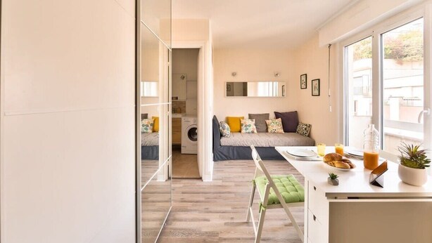 Un espacio habitable compacto con kitchenette, comedor y cama.