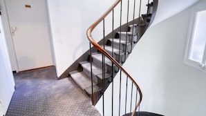 En spiralformet trappe med gelænder i metal og tæppe beklædte trin.