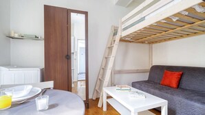 En kompakt bolig med køjeseng, sofa, spisebord og tekøkken.