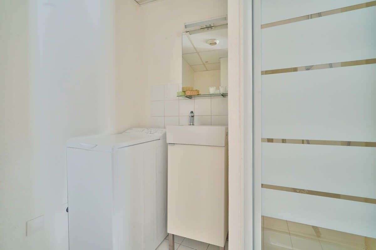 A bathroom with a white radiator, a sink, and a mirror.