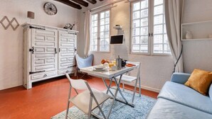 Una habitación con una mesa de comedor, sillas, un sofá, un armario y una ventana con cortinas.
