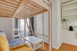 A room with a bed, a small table, a ladder, a white wardrobe, and a window with curtains. - Nicely designed Studio - Paris 17 - Mid Terms (Paris)