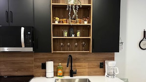 Una cucina moderna con forno a microonde integrato, lavello in acciaio inossidabile e pensili in legno.