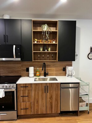 Eine moderne Küche mit integriertem Mikrowellenherd, Spüle aus Edelstahl und Holzschränken.