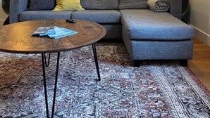 Un soggiorno con un divano grigio, un tavolino rotondo e un tappeto decorato.