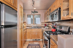 A kitchen with wooden cabinets, stainless steel appliances, a fish decoration, and a red kettle. - Casa Alto - Well-appointed, fully furnished condominium in downtown Santa Fe. (Santa Fe)