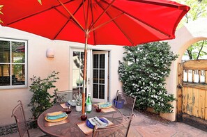 A patio with a round table, chairs, a red umbrella, and a wooden gate. - Casa Alto - Well-appointed, fully furnished condominium in downtown Santa Fe. (Santa Fe)