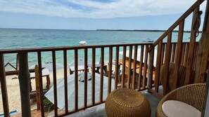 A balcony with a view of the ocean, wooden furniture, and a beach area with umbrellas. - W cabañas beach, ocean view room 202, a step away from the sea. (cartagena)