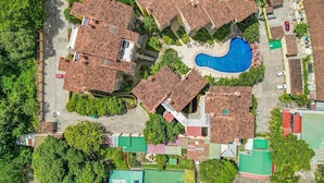 An aerial view of a residential area with multiple houses, a swimming pool, and surrounding greenery. - Sunrise Tamarindo 22 (Tamarindo)