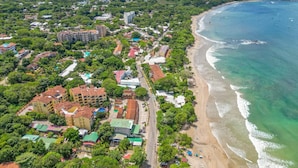 An aerial view of a coastal town with a beachfront, buildings, and greenery. - Sunrise Tamarindo 22 (Tamarindo)