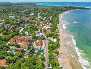 Luftaufnahme einer Küstenstadt mit Strand, Gebäuden und viel Grün.