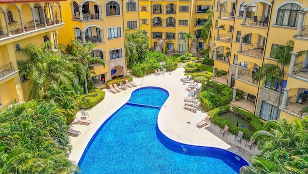 A hotel with a central swimming pool surrounded by lush greenery and multiple balconies. - Sunrise Tamarindo 22 (Tamarindo)