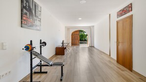 Un couloir avec un banc de musculation, un miroir et une porte.