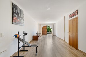 A hallway with a weight bench, a mirror, and a door. - Villa 'Santa Susanna 18' with Sea Views (Santa Susanna)