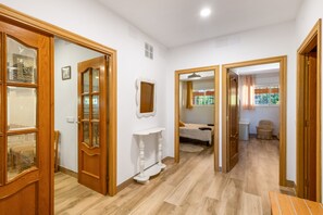 A hallway with wooden doors, a white console table, and a bed in the background. - Villa 'Santa Susanna 18' with Sea Views (Santa Susanna)