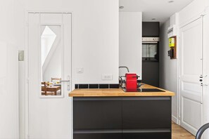 Eine moderne Küche mit einer Holzausziehtheke, einem roten Gerät und einem schwarzen Schrank.