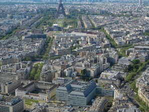 Eine Vogelperspektive auf dicht bebautes Stadtgebiet mit einem markanten Turm in der Mitte, umgeben von verschiedenen Gebäuden und Straßen.